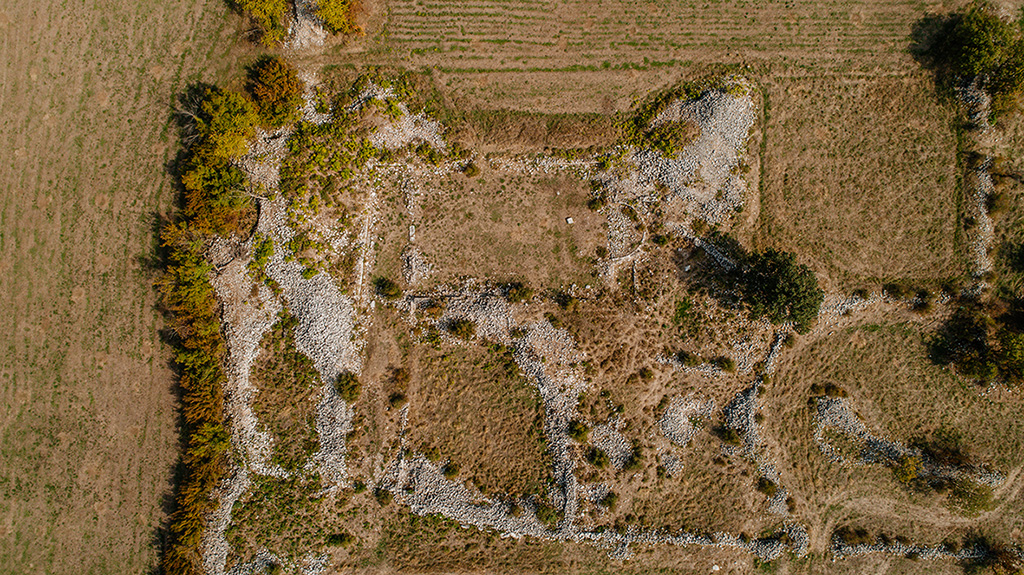 This image showcases the remains of an early Christian basilica, identified as Basilica A. The stone foundations delineate the main nave and annexes. The typical architectural plan of ancient Christian basilicas is recognizable, with a semicircular apse at the eastern end and partition walls separating different parts of the building.