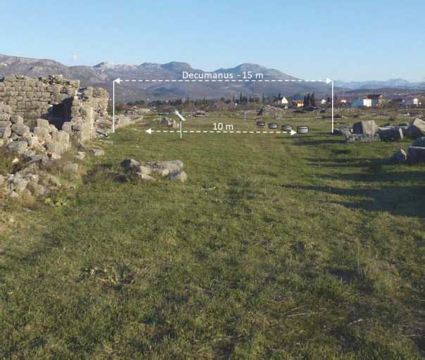 Photograph of a section of the decumanus maximus at the heart of Doclea. This main road was about 15 meters wide and formed the central axis of the urban network. Remains of Roman structures are visible on both sides of the road, highlighting its significance in the city's organization.